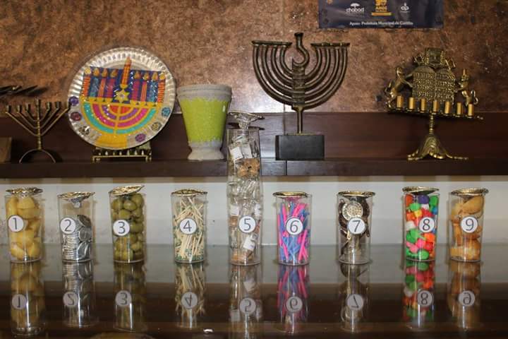Guess how many. Menorah with chanukah objects (matches, candles, coins, dreidels, potatoes, oliv ...